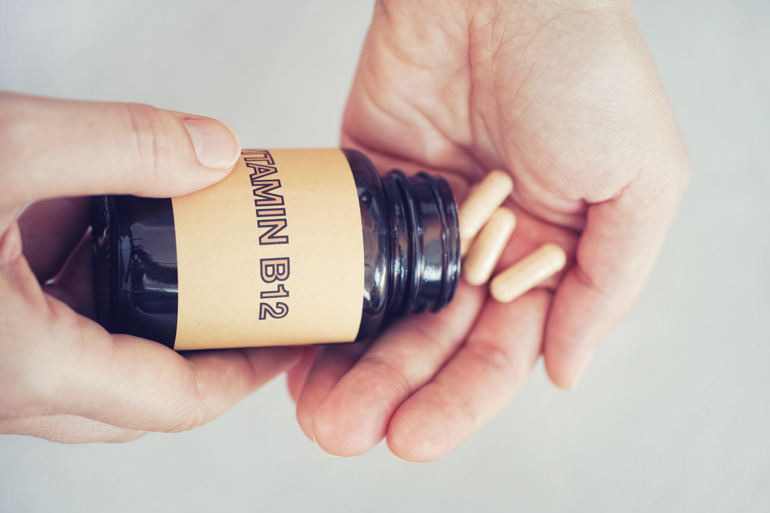 Vitamin B12 pills being dispensed from a bottle