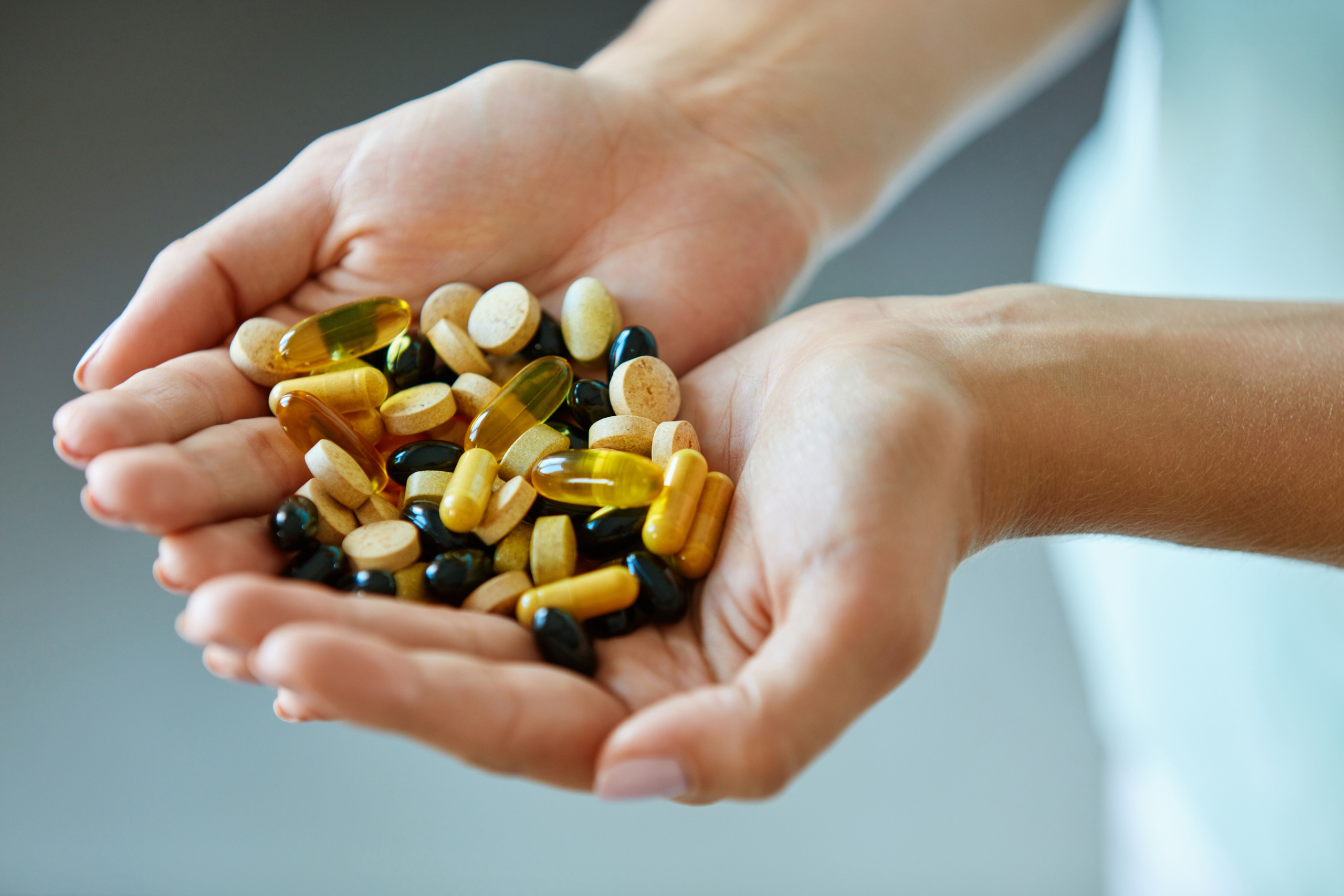 a pile of vitamins and supplements in hand