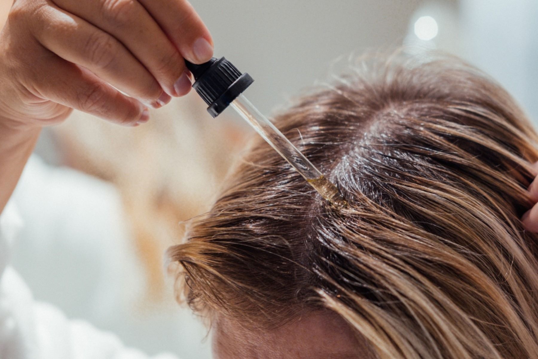 person applying hair oil to dry hair