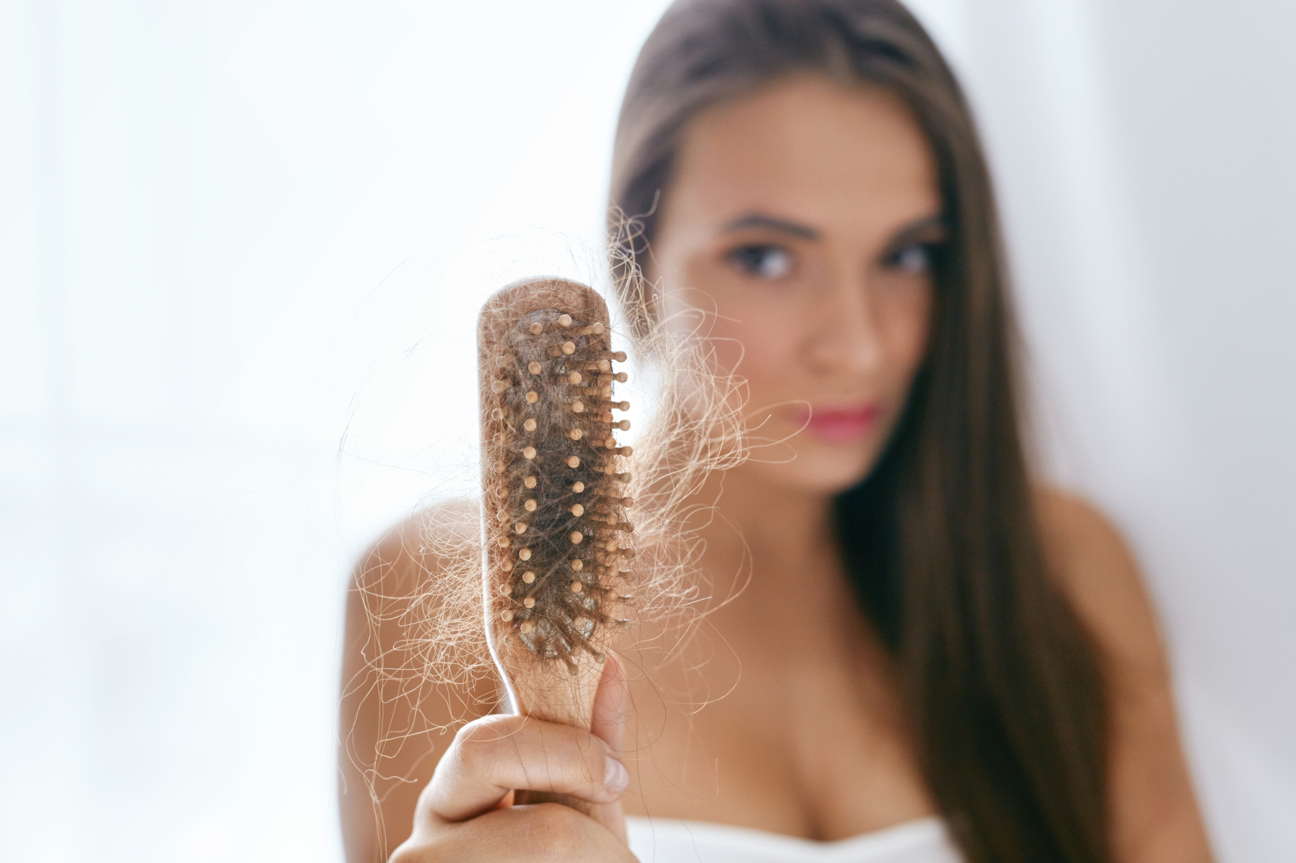 upset woman holding brush with shedded hair