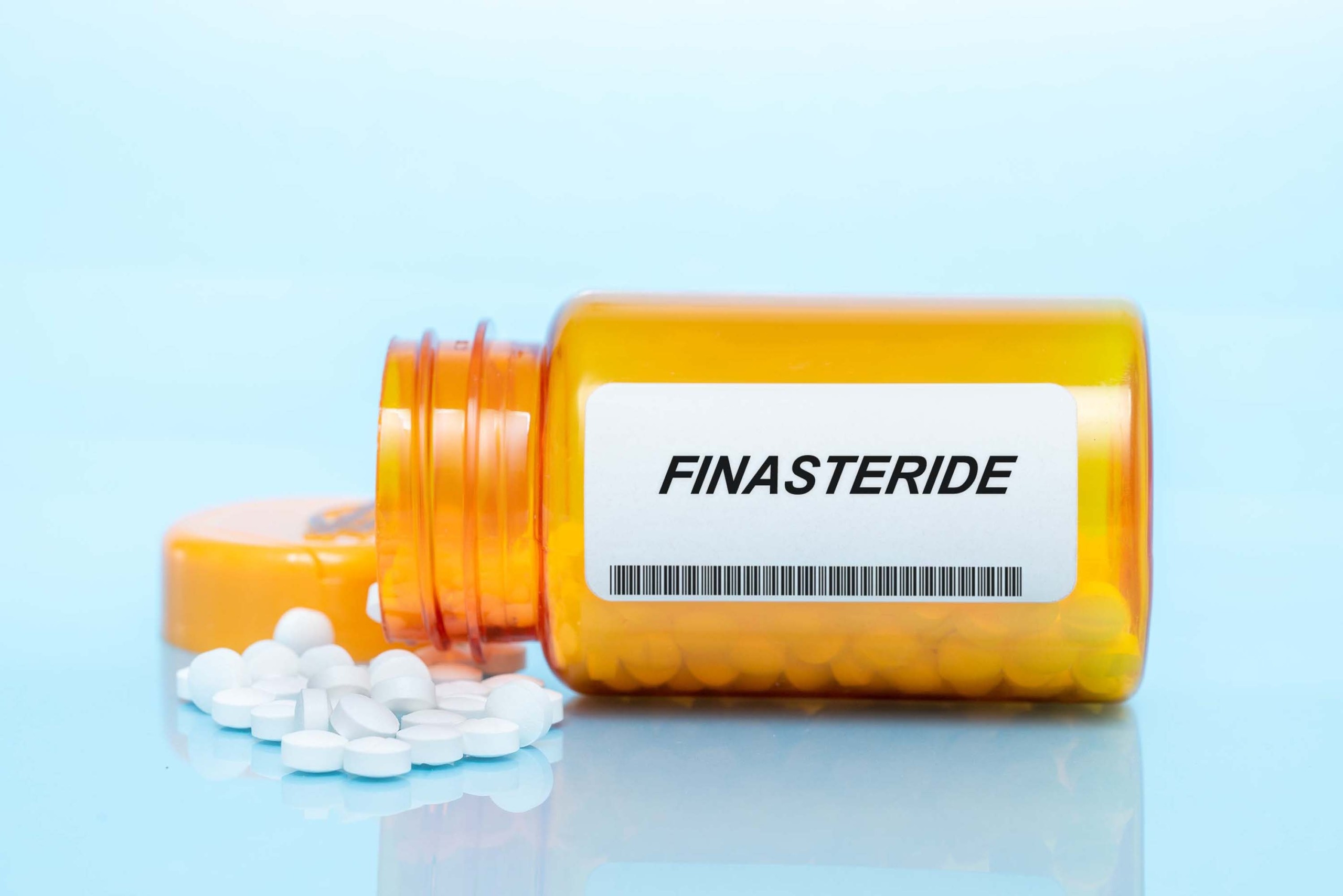 Finasteride pills spilling out of a bottle