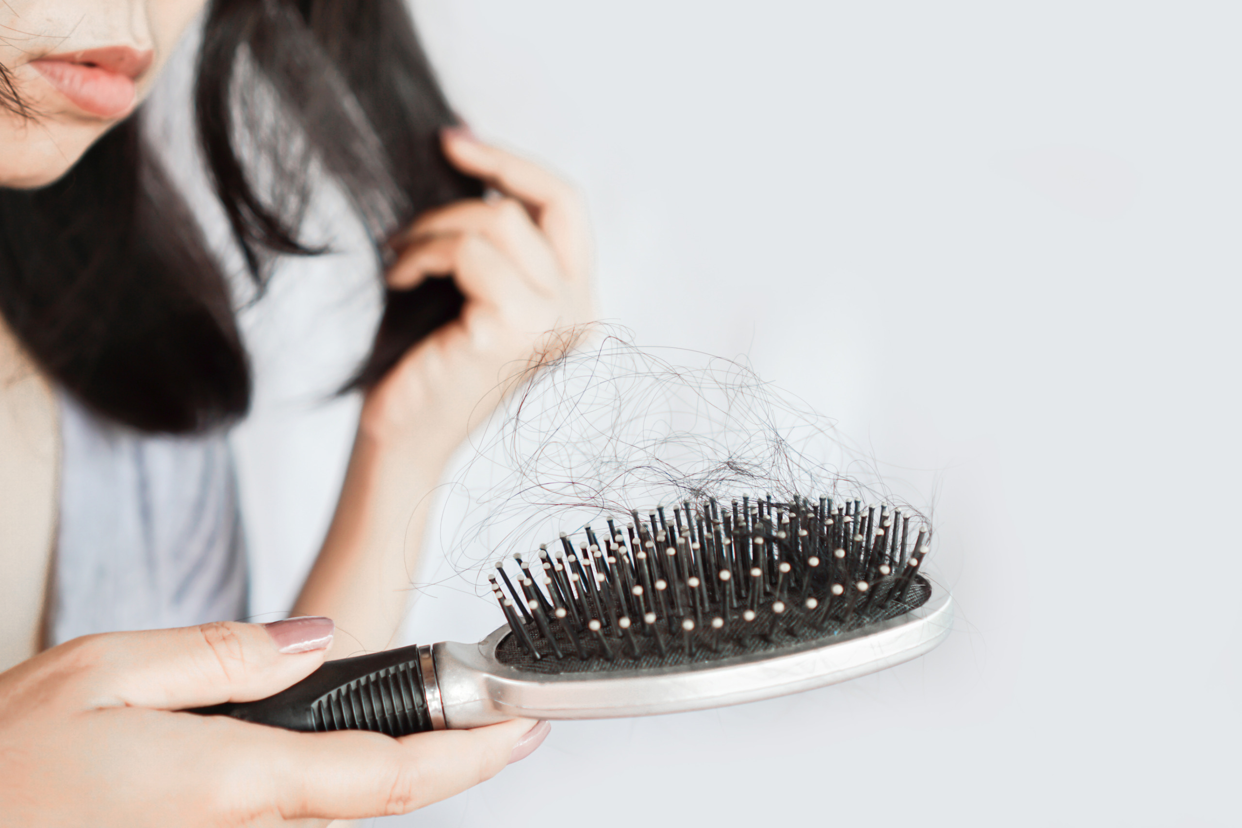 woman looking at shedded hair in hairbrush