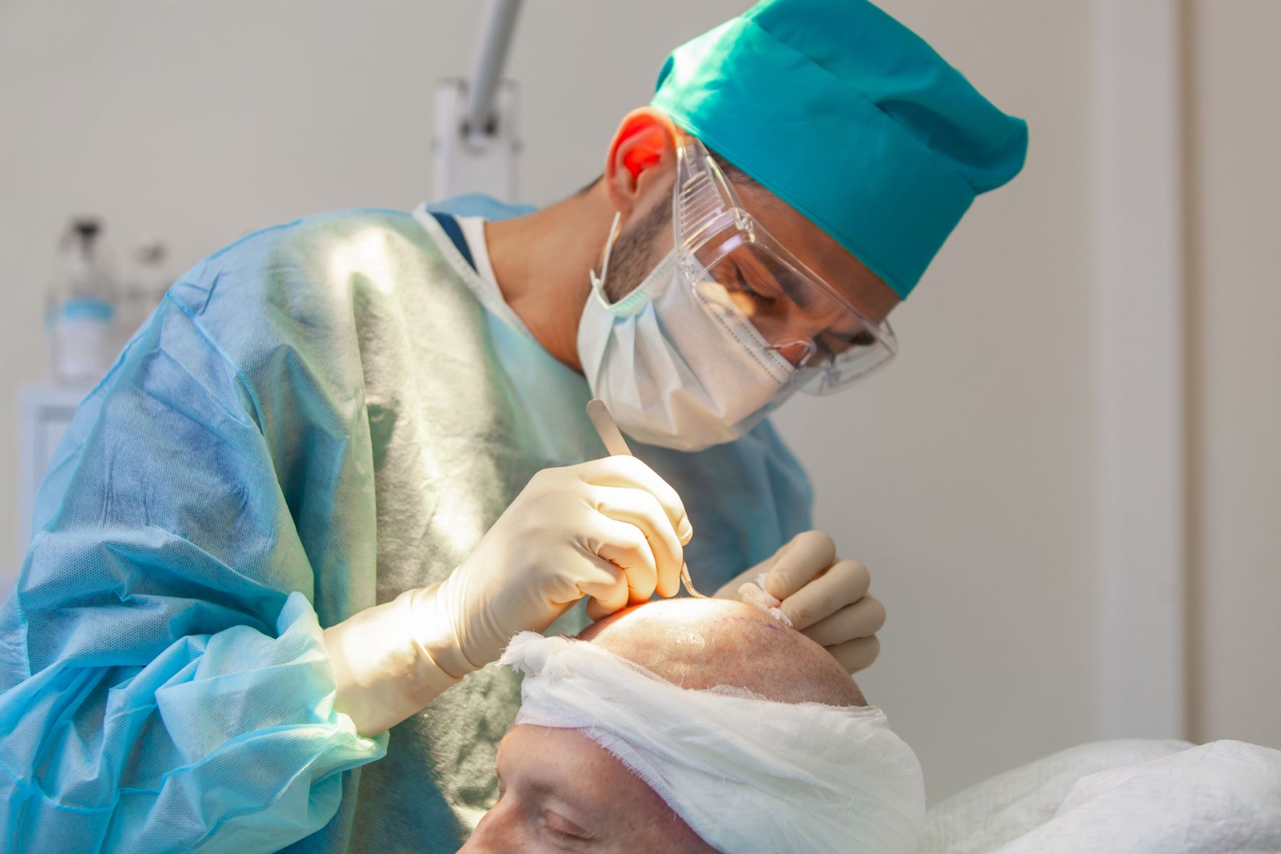 A surgeon performing a hair transplant on a male patient