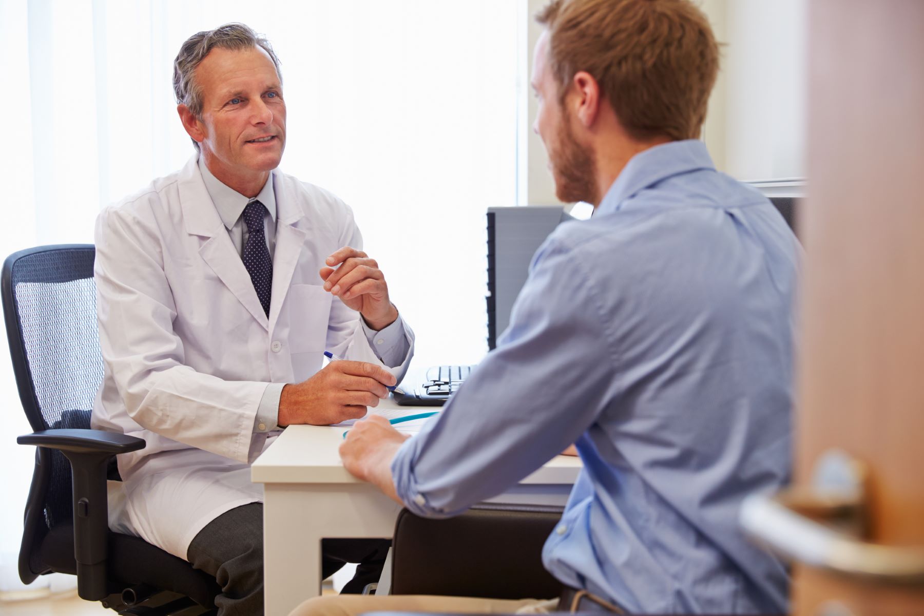 Male patient talking to a doctor in his office