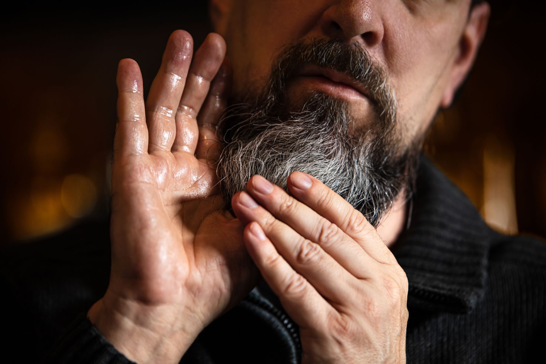 Man applying beard oil on his facial hair