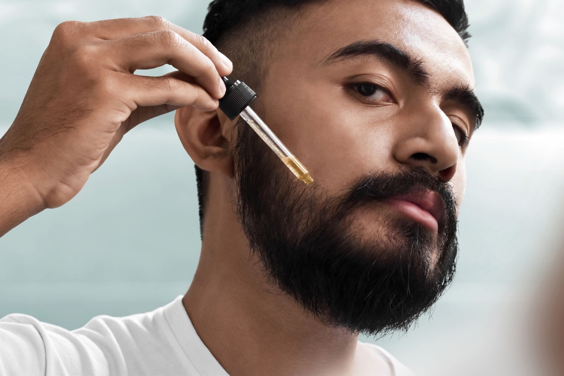 Man applying beard oil with a dropper