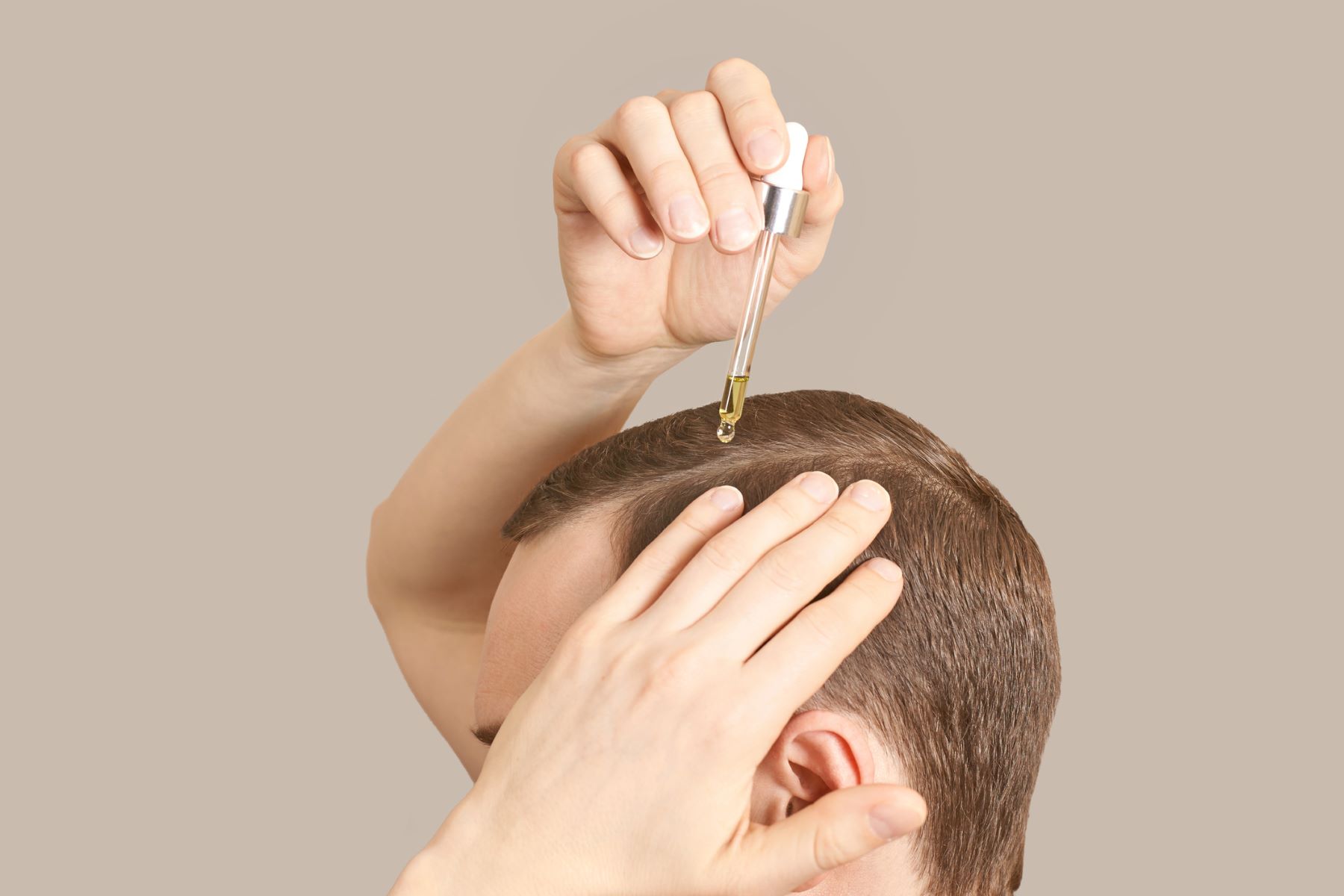 Man applying hair treatment to his scalp