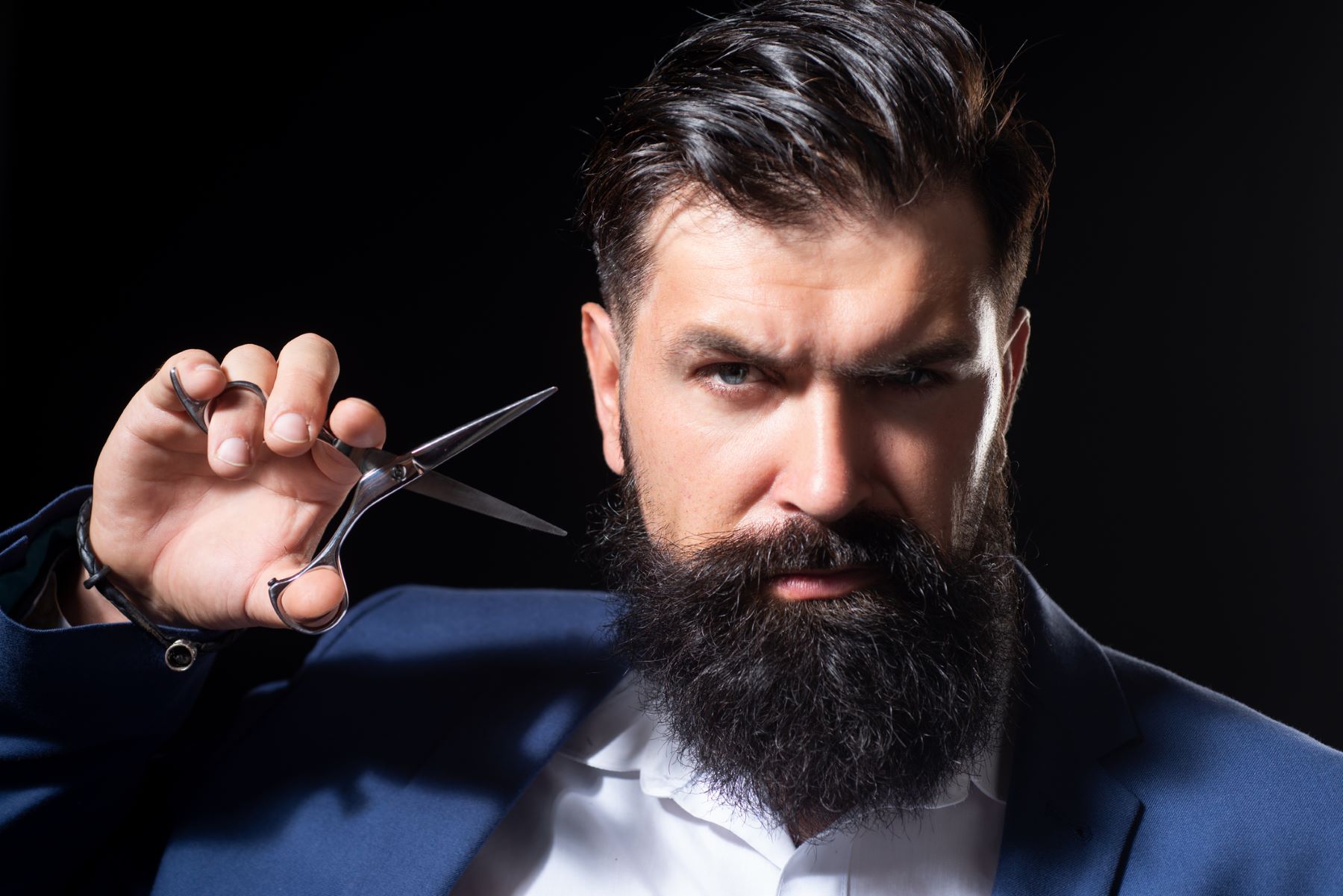 Man preparing to clip his unruly beard tufts with scissors