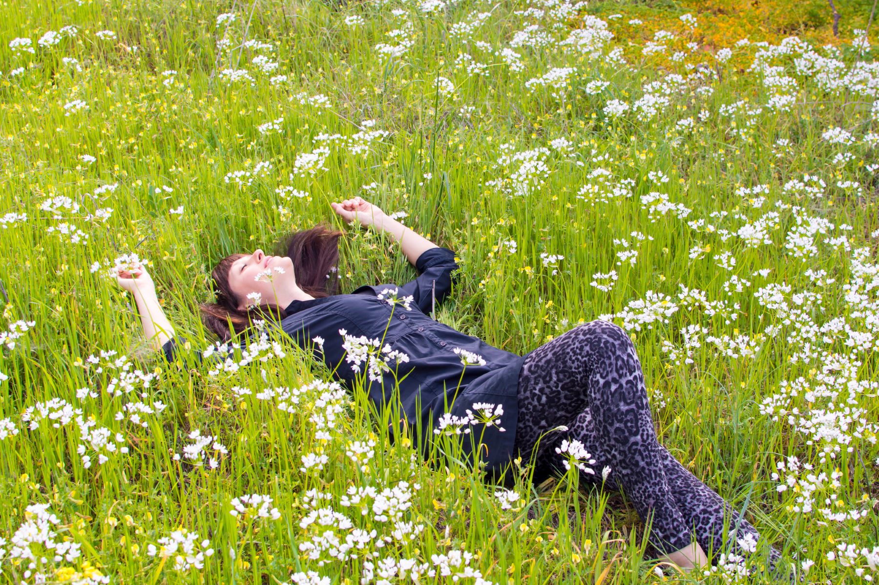 Woman reducing stress by laying in the grass