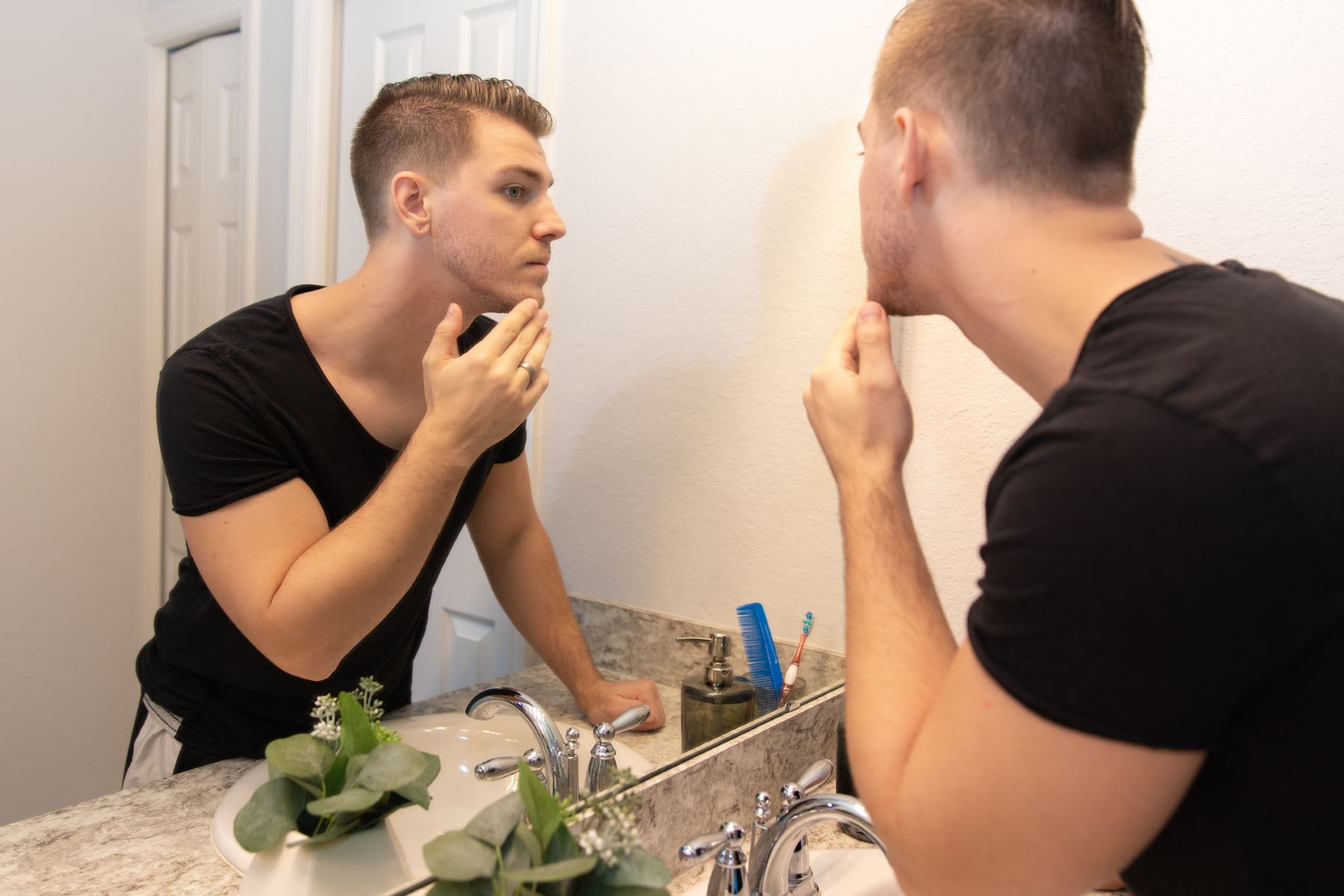 Young man checking out his sparse beard in the mirror
