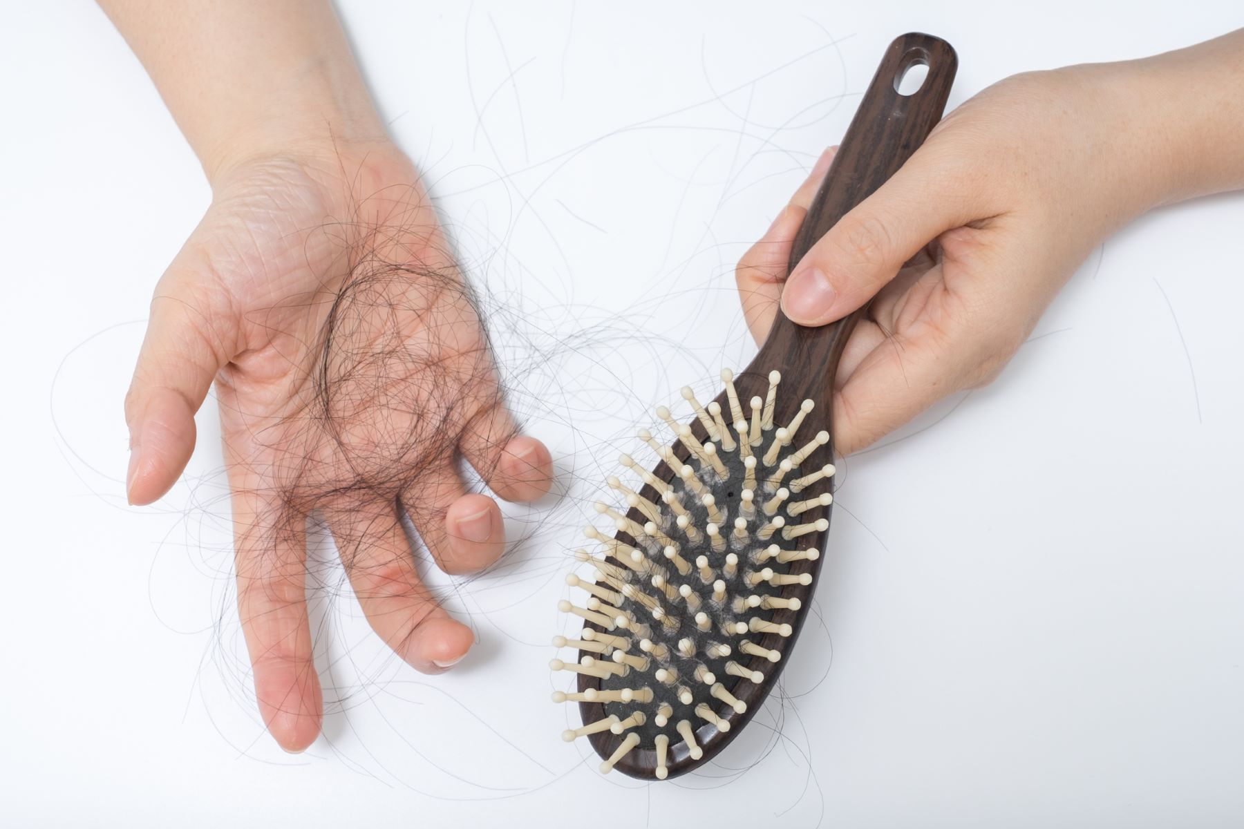 a hand showing fallen hair removed from a hairbrush