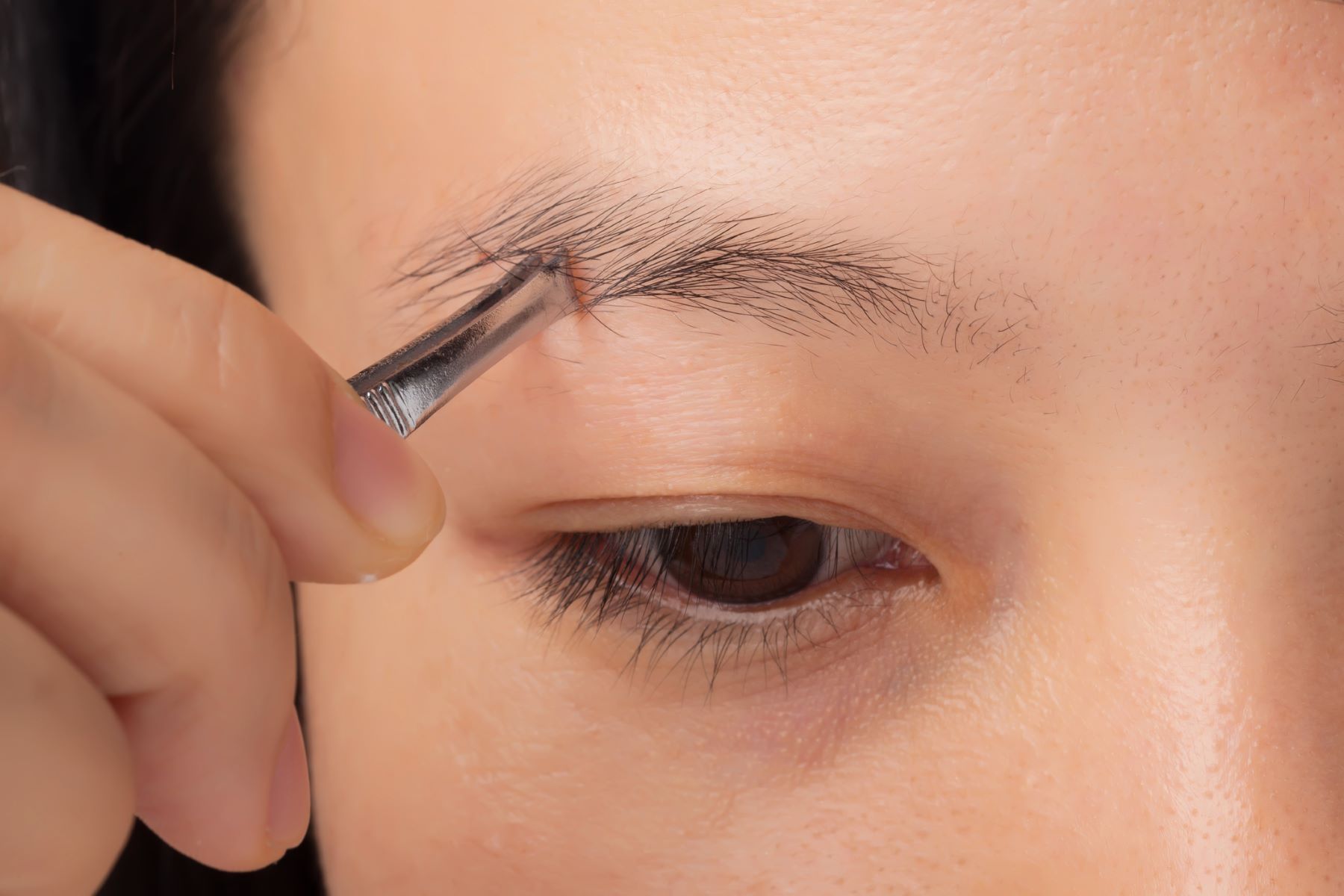 Woman plucking thin eyebrows