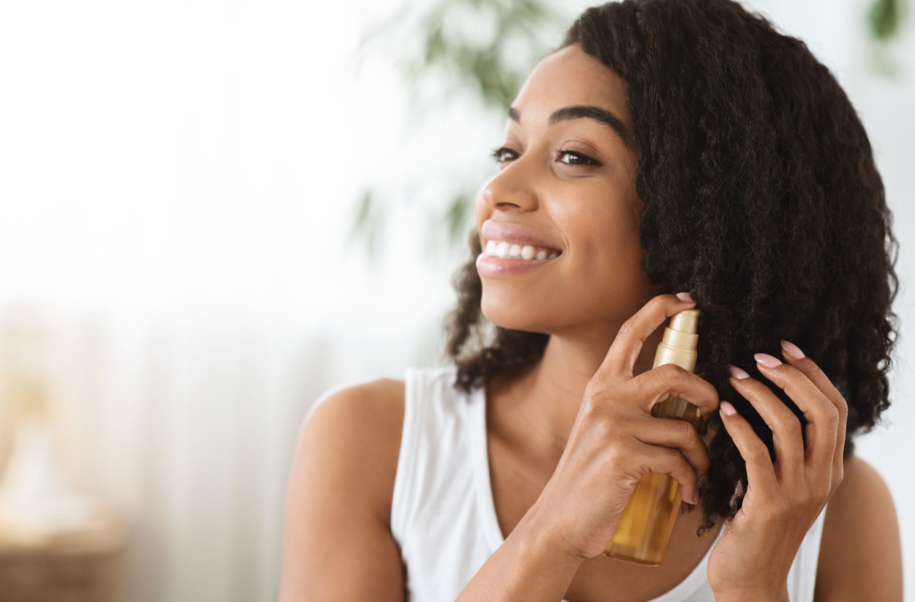 Woman with curly hair using jojoba oil