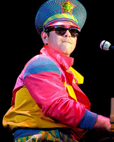 elton john wears a hat throughout a performance in the 80s