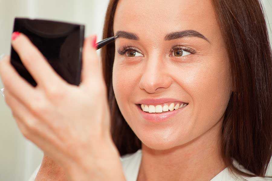 woman using an eyebrow pencil to fill in her eyebrows.