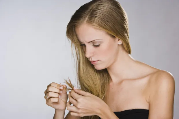 woman closely examining the ends of her hair