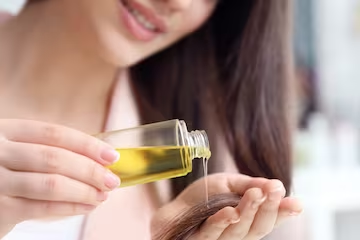 woman pouring oil onto hair
